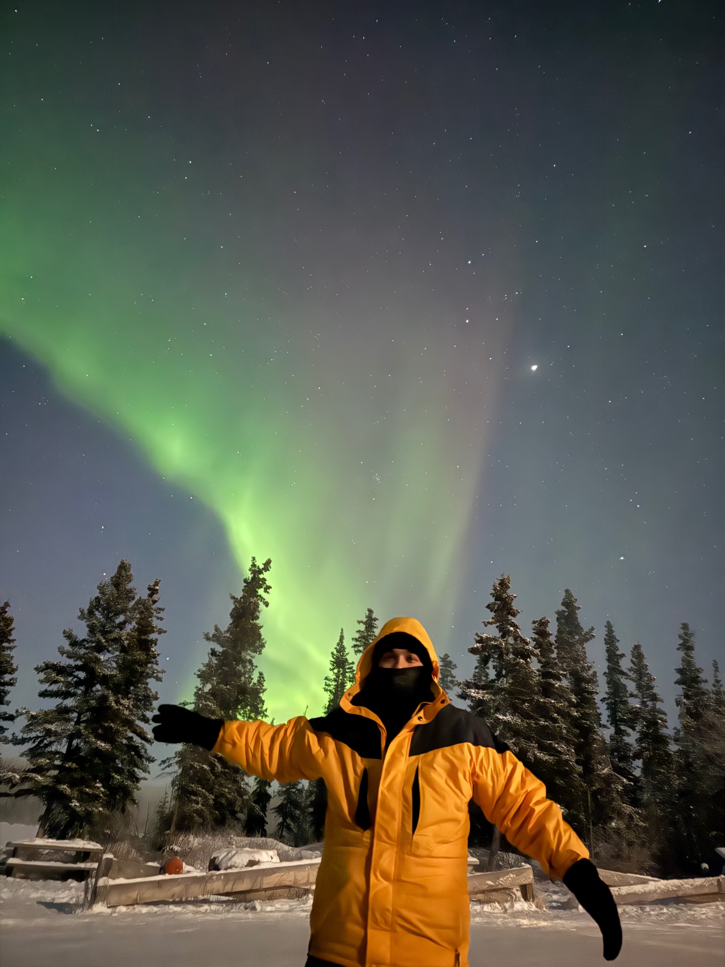 Traveler enjoying the northern lights in yellow parka